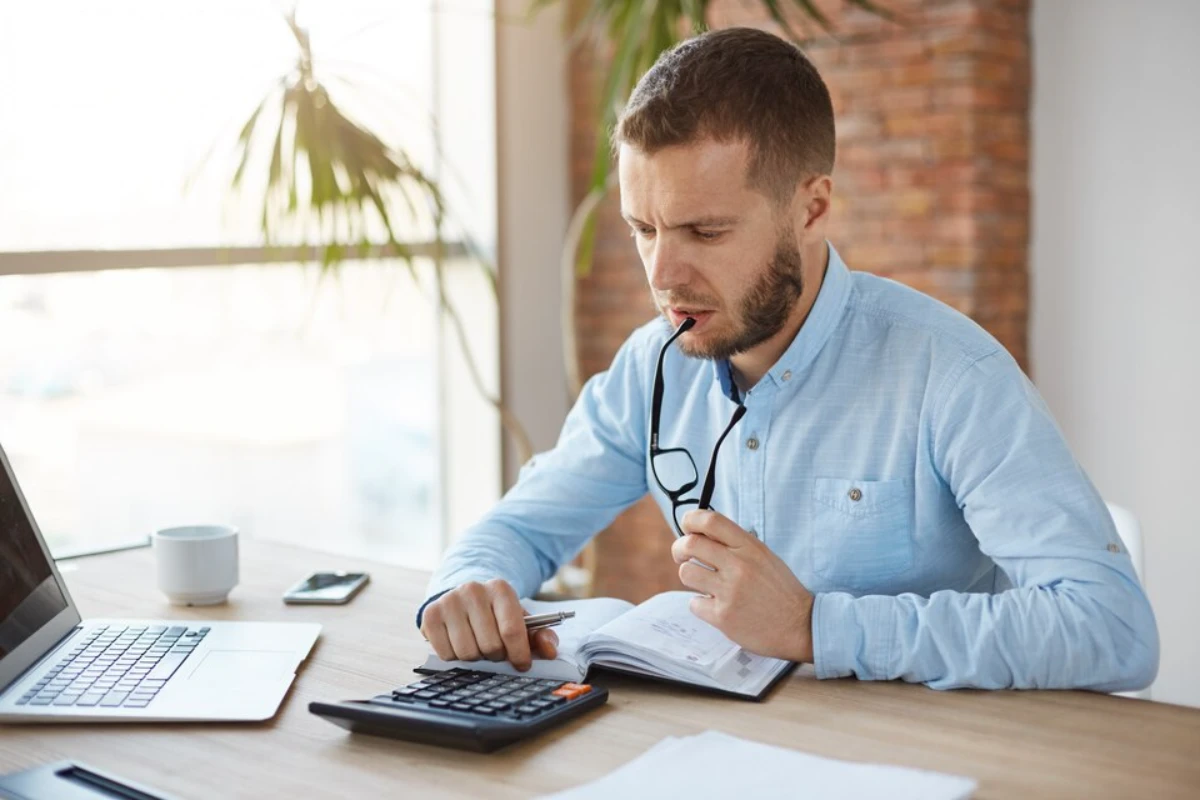 Close-up photo of a serious man calculating tax consultation fees in Bronx.