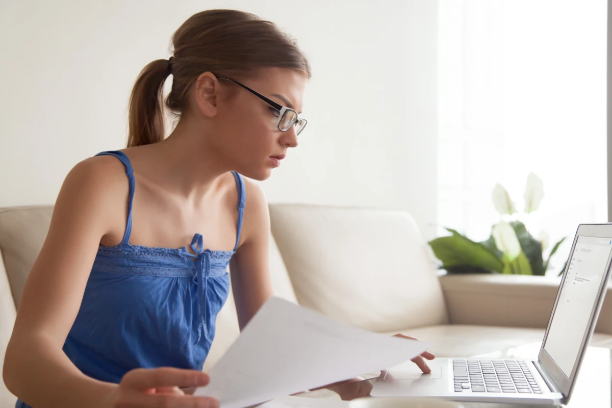 A woman reading about the drawbacks of filing a tax extension on her laptop.