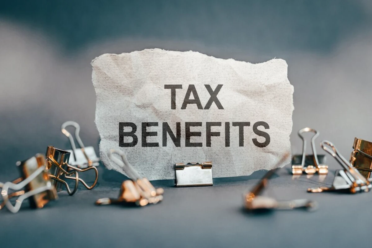 TAX BENEFITS text on torn paper on office background