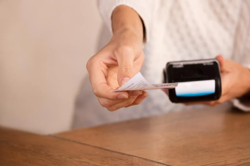 Young woman doing process payment with the bill or invoice on the POS cash terminal in a shop
