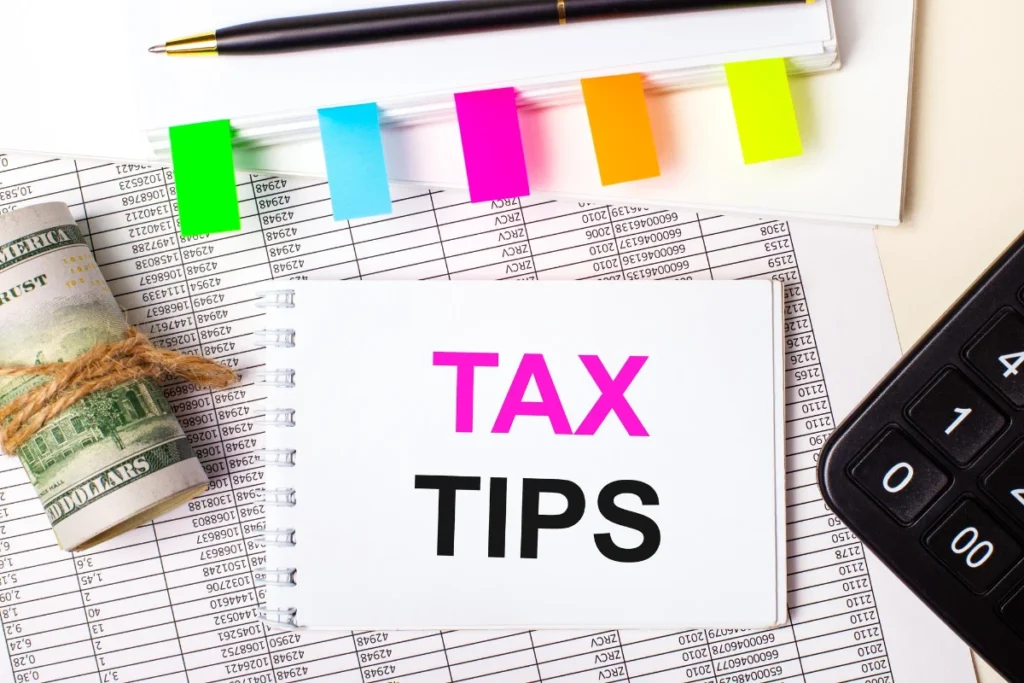 On a light background a pen dollars a notebook with the text TAX TIPS and bright stickers Business concept