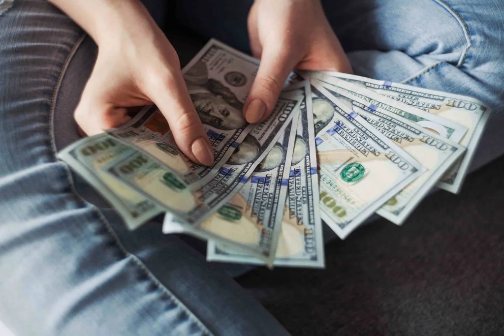 a woman having saved self employed tax money in her hand in & Near Bronx, NY